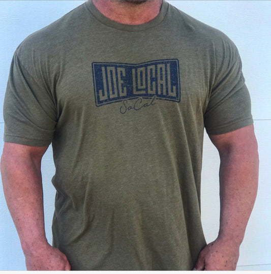 Front of the t-shirt. Military green t-shirt with navy blue Joe Local So Cal flag logo at the center of the chest. Well-fitted and comfortable t-shirt. Fabric: CVC Jersey 60% Combed Ring-Spun Cotton 40% Polyester /32 singles, 145 grams/4.3 oz Neck: Crew